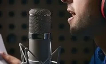 Homem em estúdio cantando com microfone e fones de ouvido, representando curso de canto e aprimoramento vocal