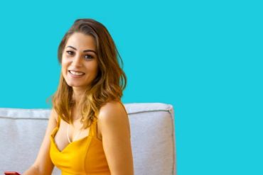 Mulher sorrindo e segurando um diploma de curso de corretor de imóveis com um fundo de casas.